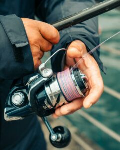 Mains de pêcheur tenant un moulinet spinning avec tresse